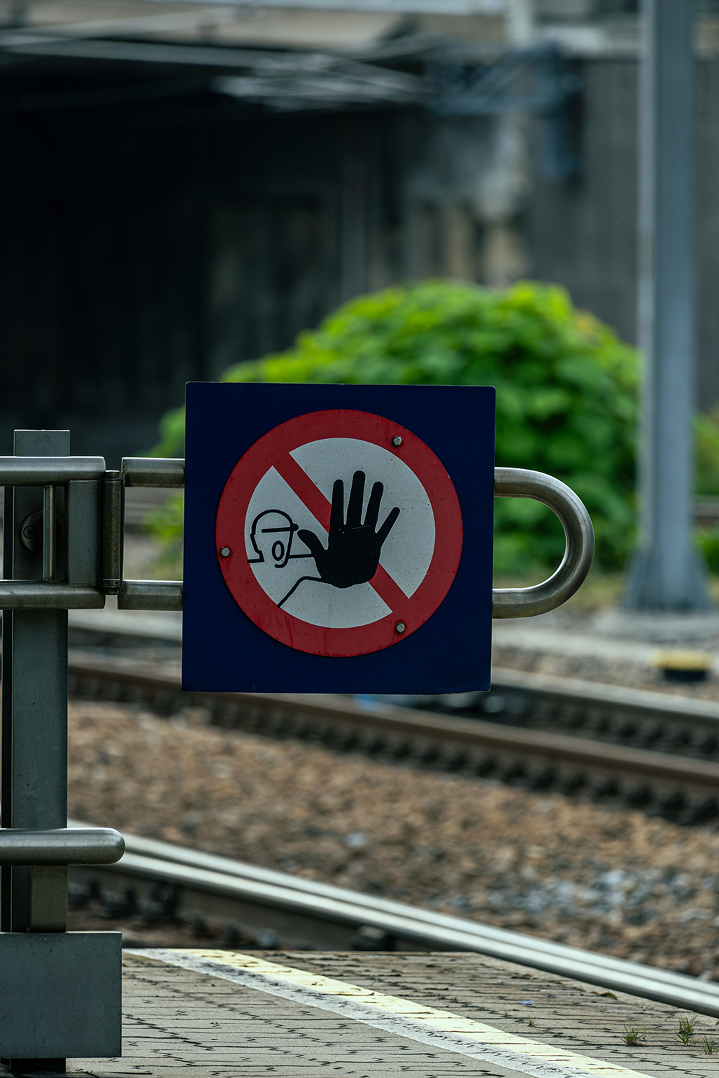 A warning sign indicating forbidden entry near railway tracks and station.